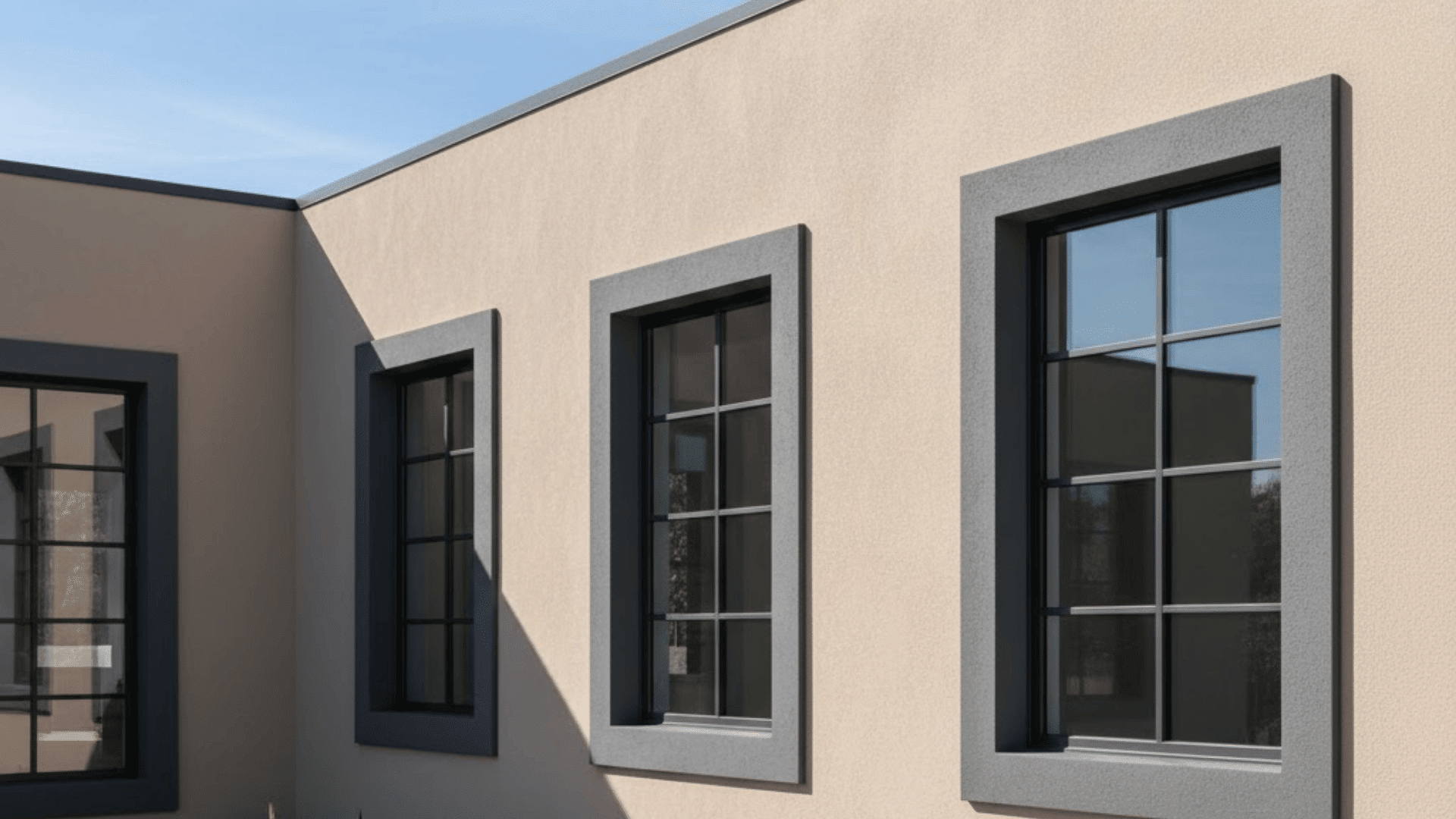 Modern exterior windows with contrasting stucco edge trim on beige contemporary house facade