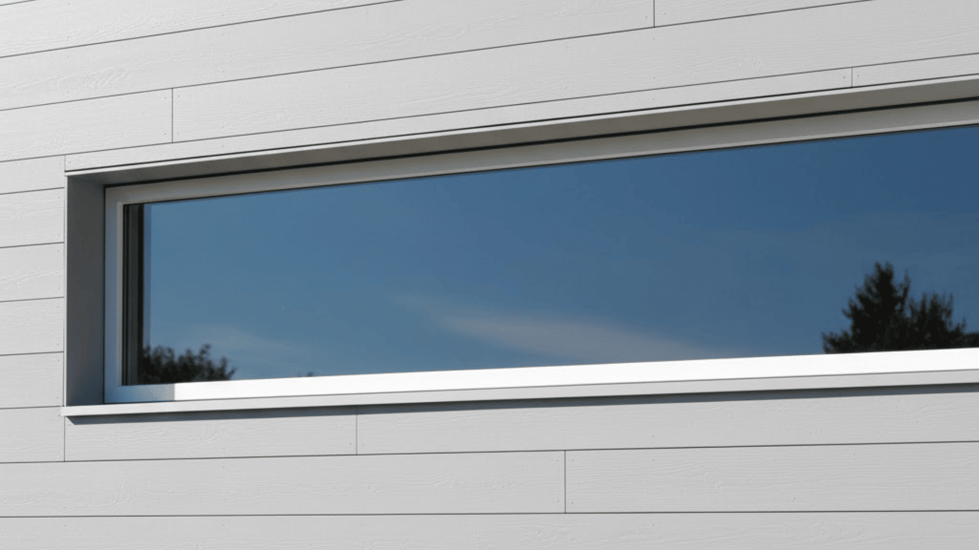 Exterior shadow gap window trim with slim horizontal glass window on modern white siding facade