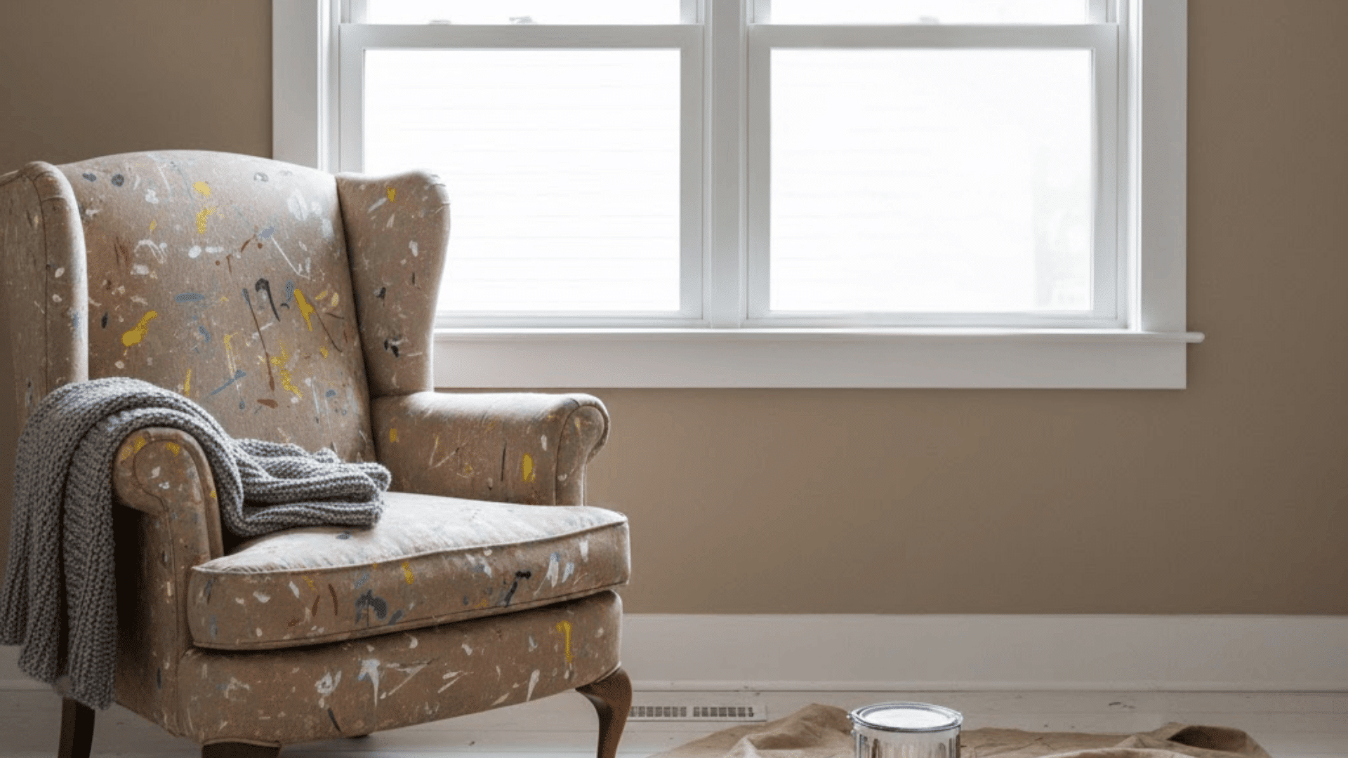 Simple white modern window trim beside cozy painted chair in neutral indoor living space