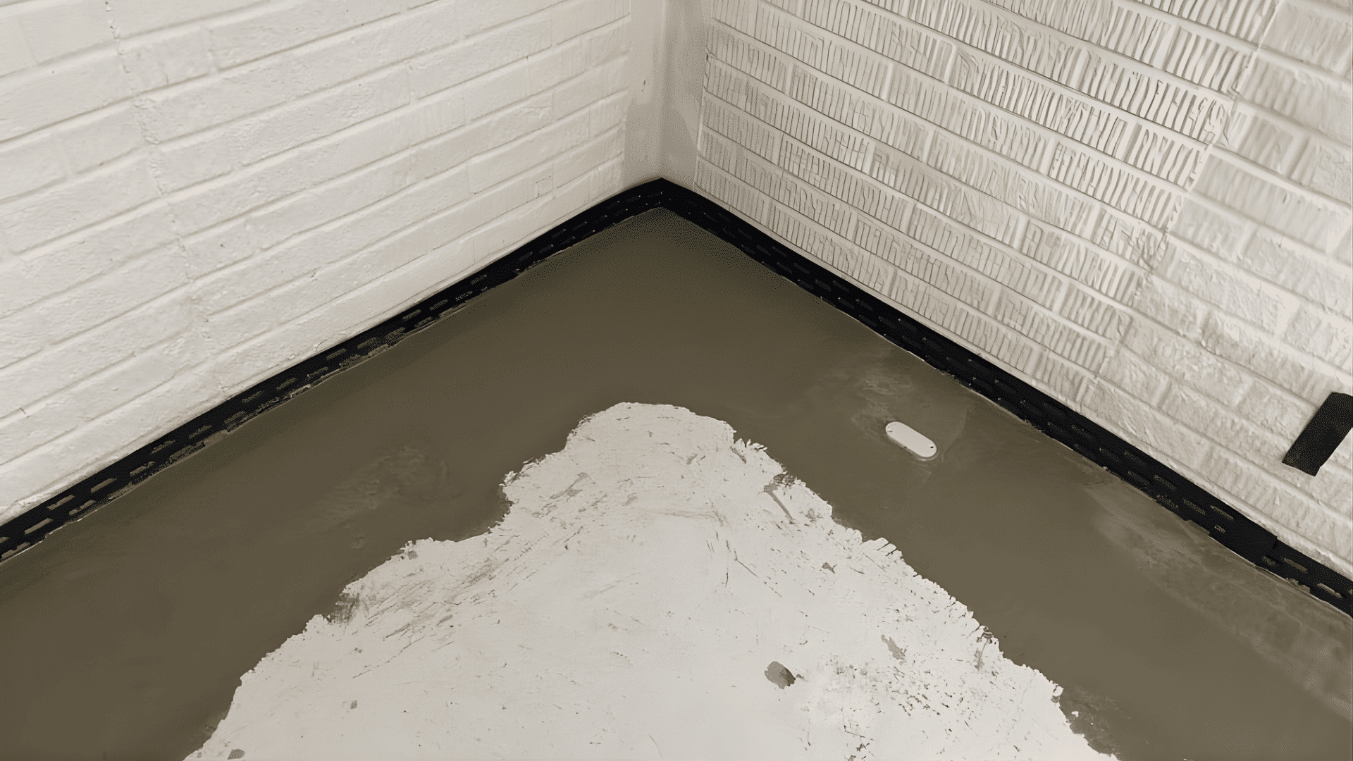 A corner of a basement room, highlighting waterproofing features and structural details.