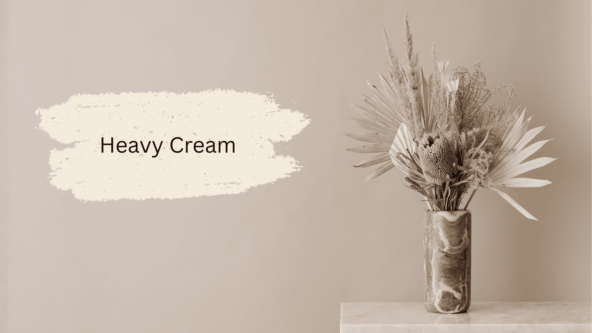 A vase with dried flowers placed on a light-colored surface, with a beige background and the text Heavy Cream beside it