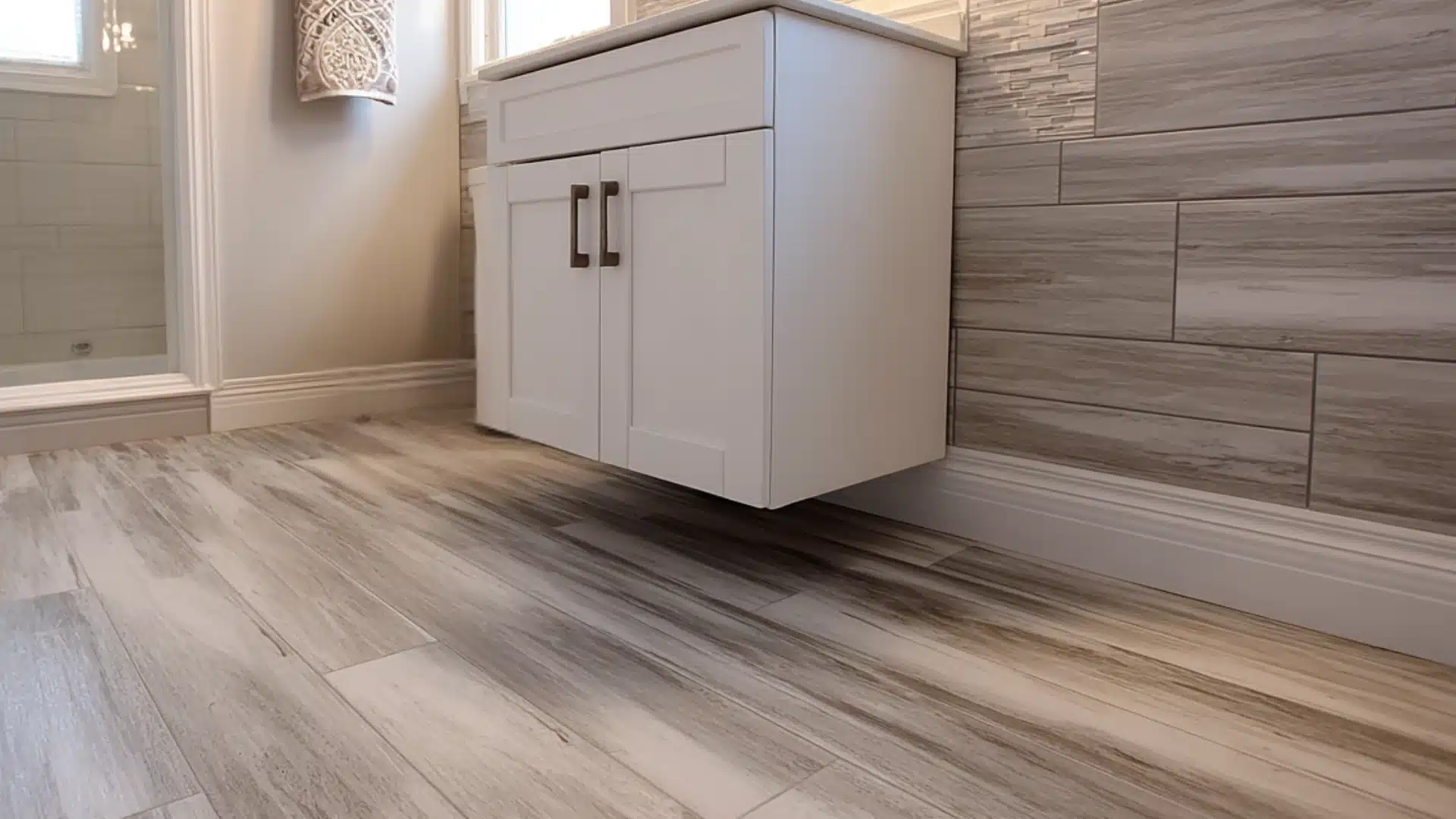 Modern bathroom with a white floating vanity marble tiles a glass shower and gray wood planks running toward a far window