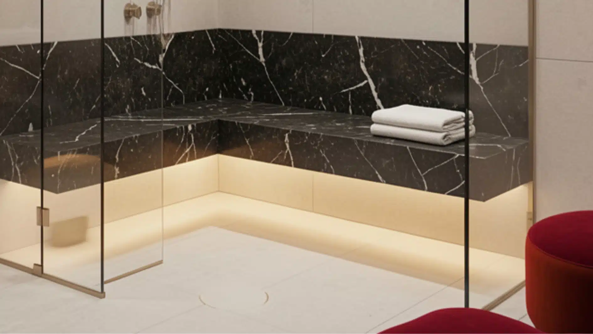 Modern shower enclosure featuring black marble with white veining for the built-in bench and wainscoting, accented by warm under-lighting.