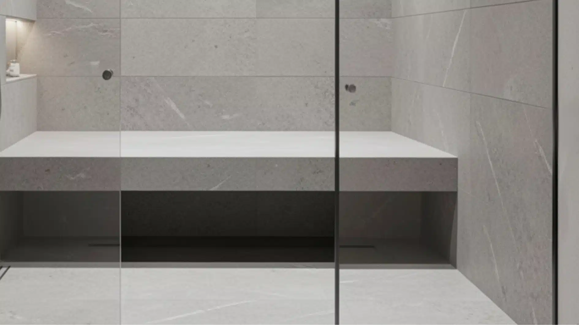 Modern walk-in shower featuring light gray, large-format stone-look tiles, a built-in shower bench, and a clear glass enclosure.