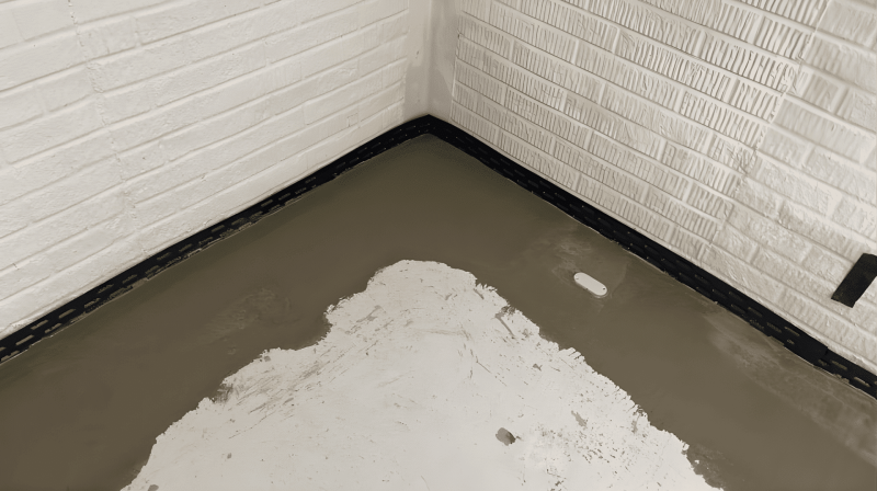 A corner of a basement room, highlighting waterproofing features and structural details.